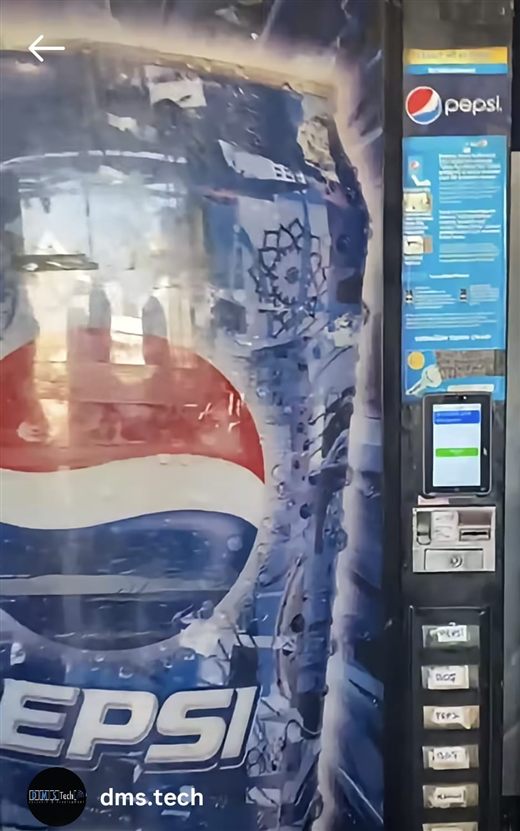 An electromechanical Dixie Narco Pepsi machine from the 1990s, a 2003 poster above it advertising purchase by phone, and a 2025 Android payment device on its front — the date readable on the device screen